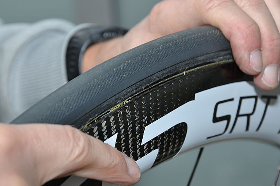 Schritt 11: Reifen justieren: Dazu kann der Reifen noch etwa mehr aufgepumpt werden. Mit den Fingern wird der Reifen so hin und her gewalkt, dass auf beiden Seiten das Nahtband gleichmäßig mit dem Felgenhorn abschließt.